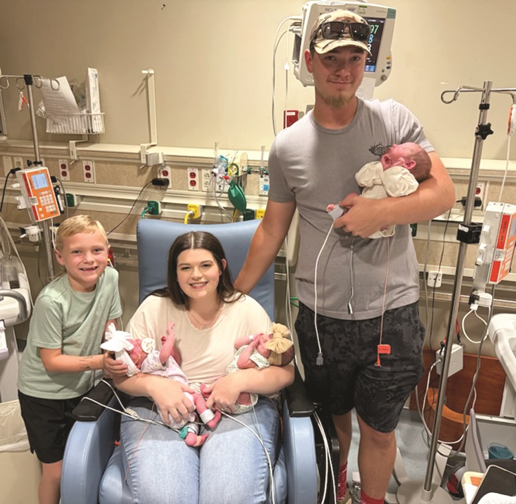 parents with newborn triplets and son